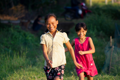 Dos niñas pequeñas corriendo y sonriendo afuera