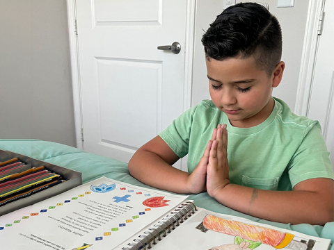 Un niño rezando en un escritorio