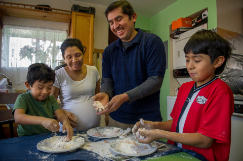 Padres y sus dos hijos preparando comida en una cocina