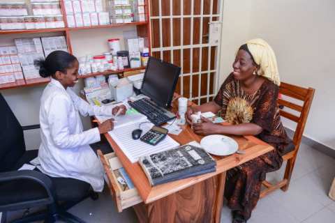 A nurse and a woman sitting at a table.