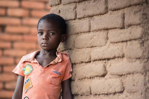 A child leaning against a brick wall