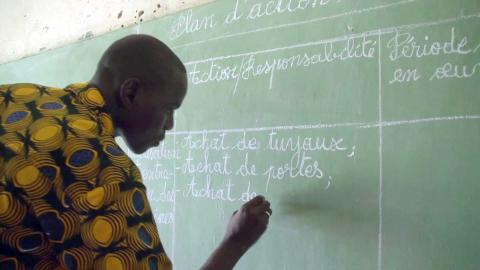A man writing on a school board.