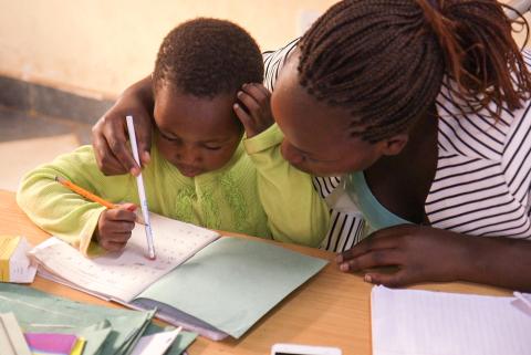 A child and a woman looking at a notebook.