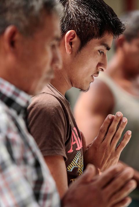 A young Guatemalan man with his head bowed in prayer