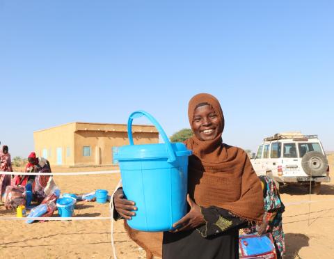 A woman holding a bucket from a distribution.