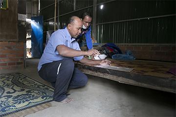 Sovanna, left, gives Bung his medicine at sunrise each morning, keeping track in a record book they received from the Ministry of Health.