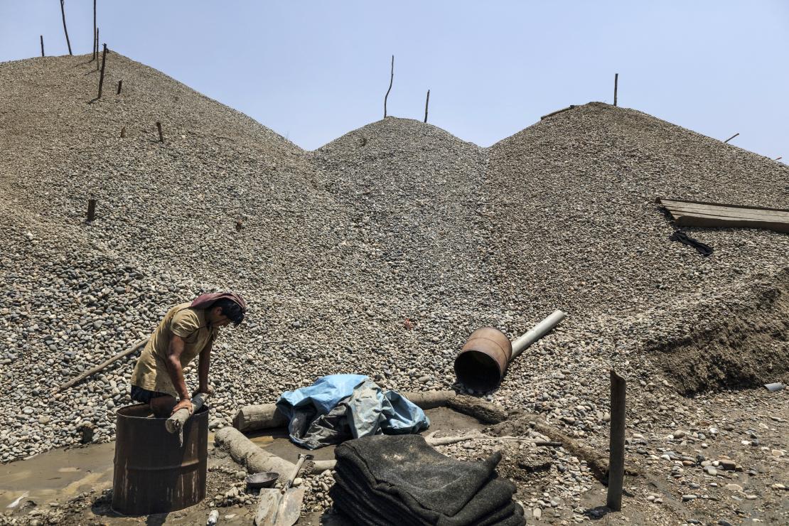 Miner Milo Hurtado, 24, is seen “steeping” sediment in a barrel with water mixed with mercury to separate the minerals and obtain gold. Photo by Oscar Leiva/Silverlight for CRS