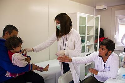 Dr. Sandra Mrdja examines a sick Syrian child with help from translator Kemal El Shairy, at the Vasariste refugee aid point in Kanjiza. Photo by Kira Horvath for CRS
