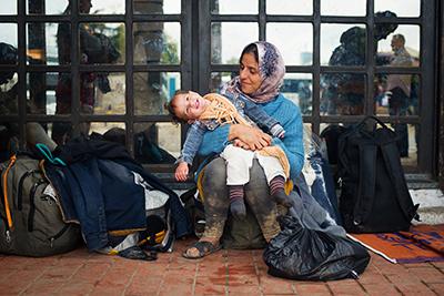 Zaineb plays with her 1-year-old daughter, Maria, at a Belgrade bus station while waiting for transportation to the Hungary border. She had been traveling for 22 days and hoped to reach Sweden where she has a brother. Photo by Kira Horvath for CRS