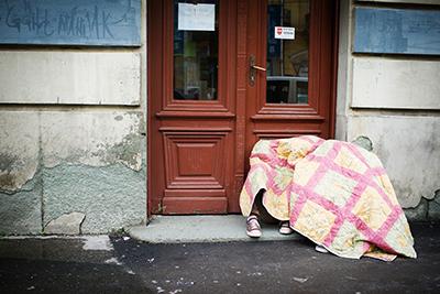 Refugees passing through Belgrade sleep on the street, seeking warmth under a quilt. Rain and cold temperatures have made this already miserable journey much harder for the thousands feeing their homelands for Europe. Photo by Kira Horvath for CRS