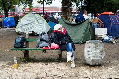 A woman sleeps on a park bench near the Belgrade bus station, where refugees pitch tents and await transportation to the Hungarian border. Photo by Kira Horvath for CRS