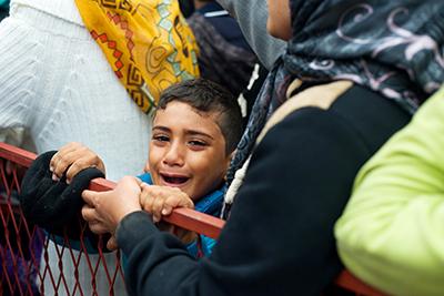 A Syrian boy, jostled by the crowd, cries as he waits in line for relief items in Belgrade. Photo by Kira Horvath for CRS