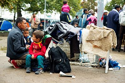 A refugee family waits for transportation to the Hungarian border at a park near the Belgrade bus station. Photo by Kira Horvath for CRS