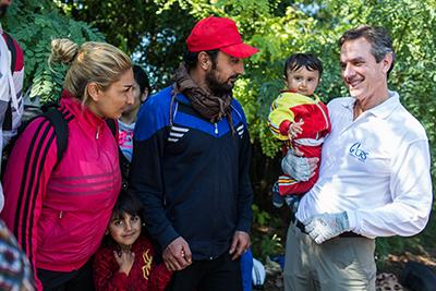 CRS Chief Operating Officer Sean Callahan holds 11-month-old Siad from Syria as his family prepares to cross the border from Serbia into Croatia. The family of five hopes to reach Germany. Photo by Andrew McConnell for CRS