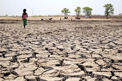 A child walks across the dried-out basin of what used to be a watering hole. Zimbabwe has been hit hard by the effects of El Niño and climate change, which has resulted in an extended drought. Photo by Nancy McNally/CRS