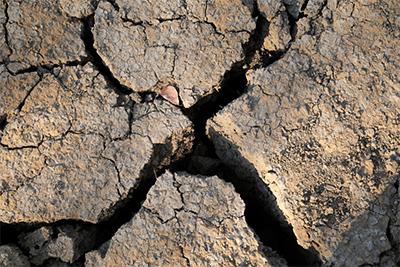 Cracked earth is all that remains of a former watering hole.  People, their livestock and indigenous animals all once relied on water from areas now completely dried. Photo by Nancy McNally/CRS