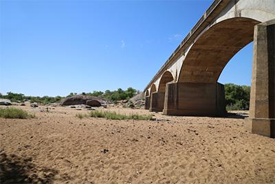 Bridges that once stood above rushing rivers now arch over nothing but sand. Many seasonal rivers in Zimbabwe dry up at certain times every year, but since the drought even perennial rivers have evaporated. Photo by Nancy McNally/CRS