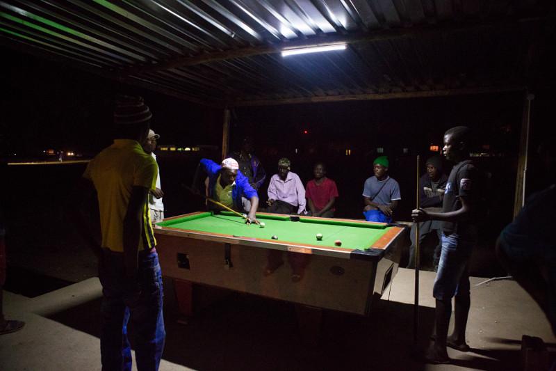 In Beitbridge, Zimbabwe, young men play billiards outside under a single light. Photo by Elie Gardner for CRS