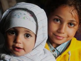 Syrian refugee Obama Basheer, holds her sister, Joud, inside a refugee aid station in the Kanjiza, Serbia. Syrian refugees arrived by double-decker bus from Belgrade, CRS is assisting the Syrian people in transit all through the region.