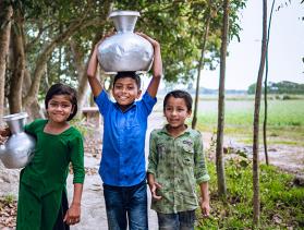 3 Bangladeshi children carry jugs of water