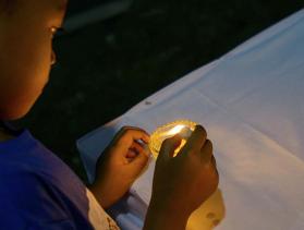 boy in Philippines lights a votive candle