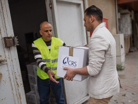 A man gives another man box with emergency supplies
