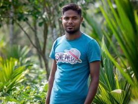 Man from Bangladesh stands among plants