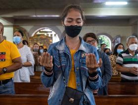 people stand and pray in church pews