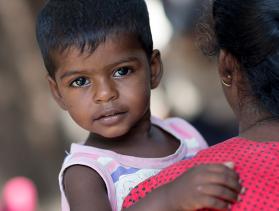 Little boy from Sri Lanka held by mother looks at camera
