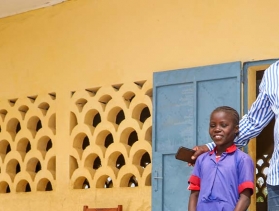 teacher stands with two of his fifth-grade students in Cameroon