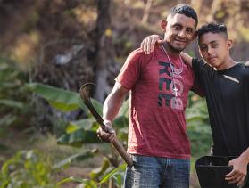 Father and son stand together in field 