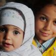 Syrian refugee Obama Basheer, holds her sister, Joud, inside a refugee aid station in the Kanjiza, Serbia. Syrian refugees arrived by double-decker bus from Belgrade, CRS is assisting the Syrian people in transit all through the region.