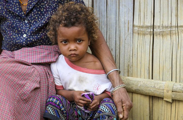 A girl sits in front of her home
