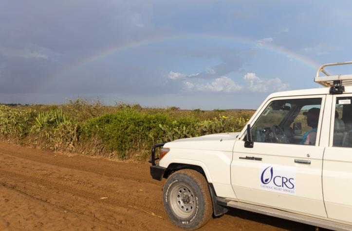 CRS vehicle on a dirt road with a rainbow in the sky.