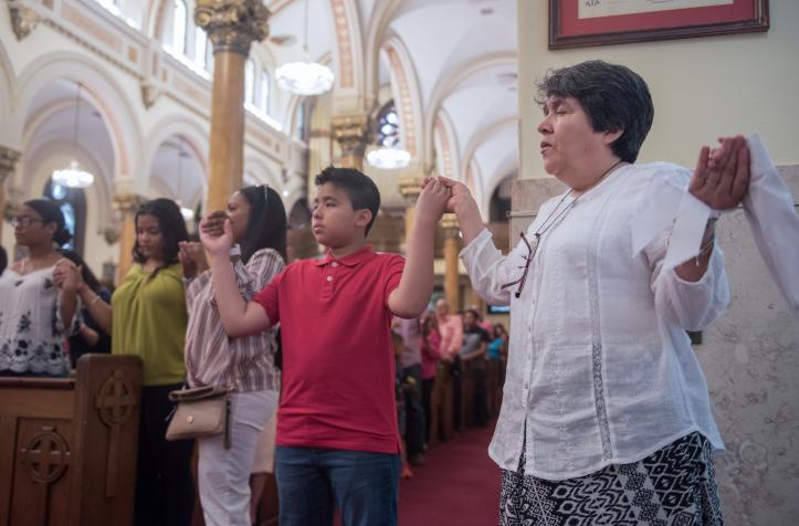 Worshippers praying hand in hand during Mass in a church.