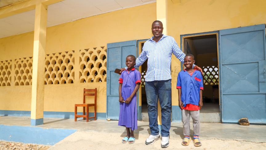 teacher stands with students at school in Cameroon
