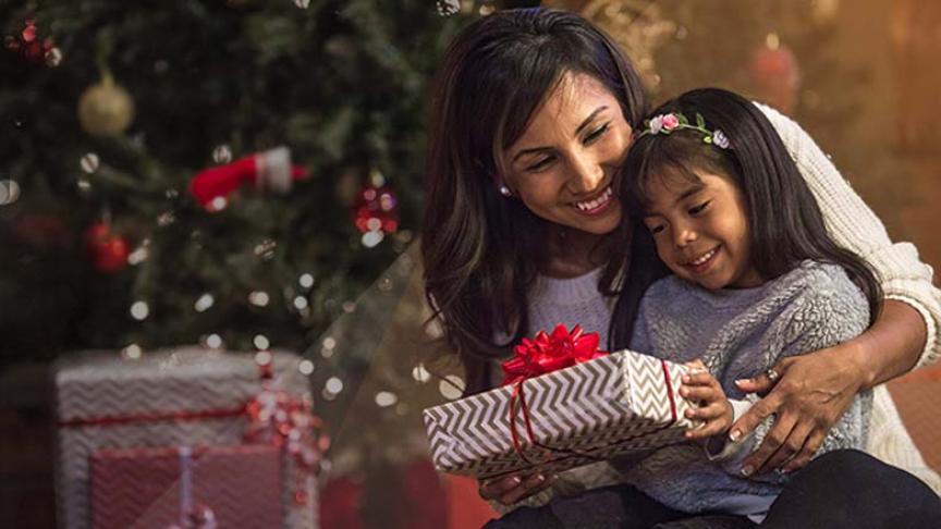 A woman and a child in front of a Christmas tree.
