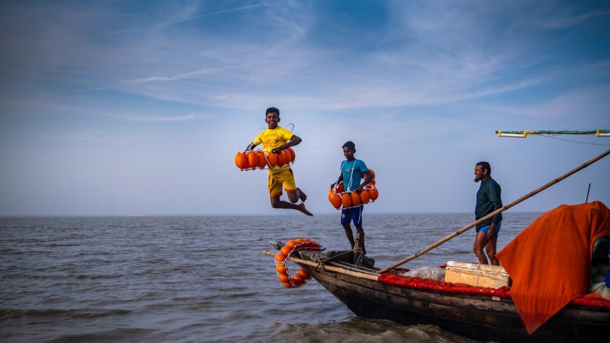 A boy jumping in the water from a boat.