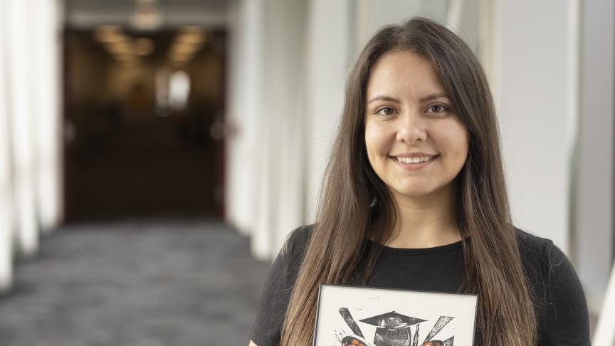 Una joven artista muestra orgullosa una pintura de una mariposa.