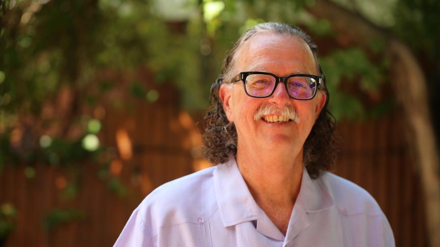 Retrato de un señor con camisa blanca sonriendo a la cámara.