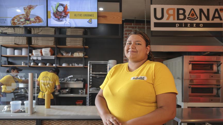 Joven posa ante la cámara en su puesto de trabajo como gerente administrativa en una pizzeria.
