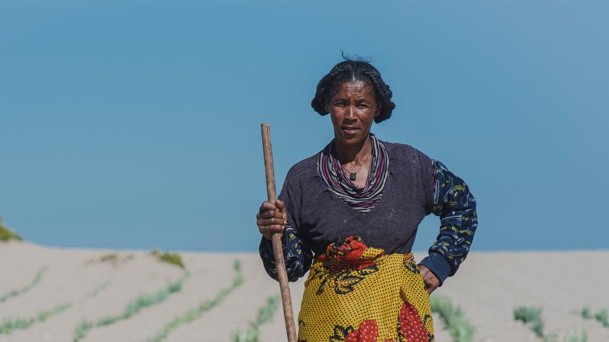 woman posing with farming tool on sand dune
