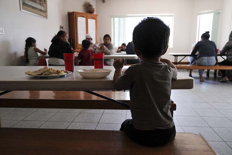 young boy eats lunch in a shelter in Mexico